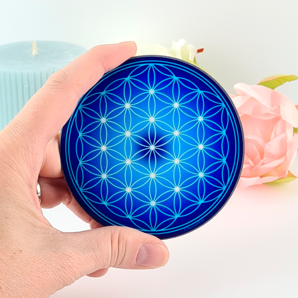 Main tenant une fleur de vie bleue, symbole de centrage et d’alignement intérieur dans la pratique de la Phronesis