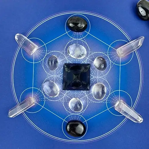 Vista aérea de una rejilla de cristal sobre un tapete del Cubo de Metatrón, que ilustra la armonización energética y la geometría sagrada