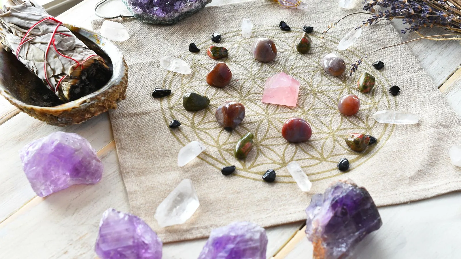 Rejilla de cristal de la Flor de la Vida con piedras y una varita de salvia junto a ella, utilizada para armonizar la energía y purificar el espacio