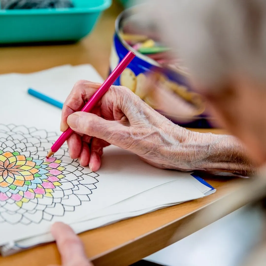 Ältere Frau, die ein Mandala ausmalt, eine beruhigende Aktivität, die Entspannung, Konzentration und inneres Gleichgewicht fördert