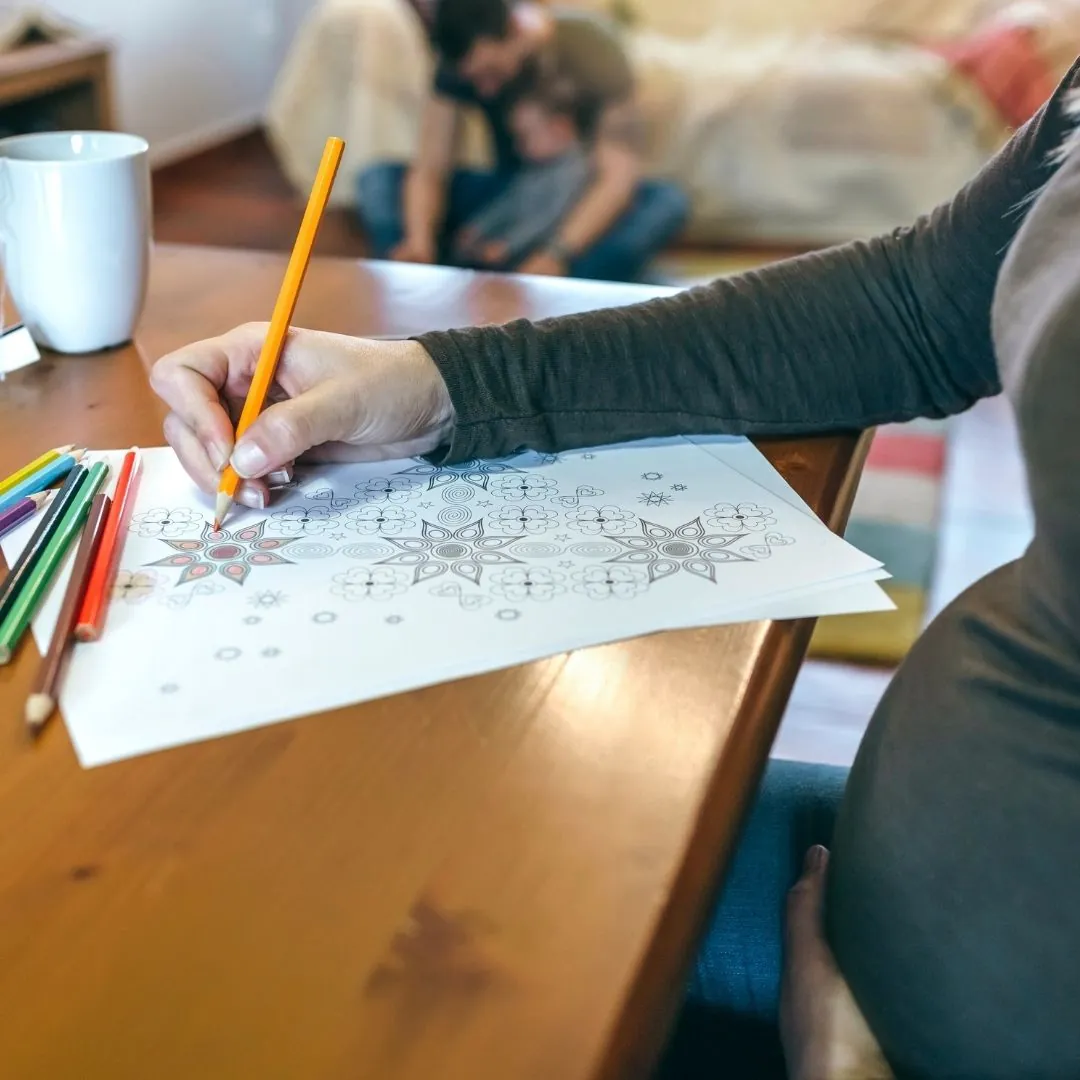 Schwangere Frau, die ein Mandala ausmalt, nutzt Kreativität, um Entspannung, inneres Gleichgewicht und die Verbindung zu ihrem Baby zu fördern