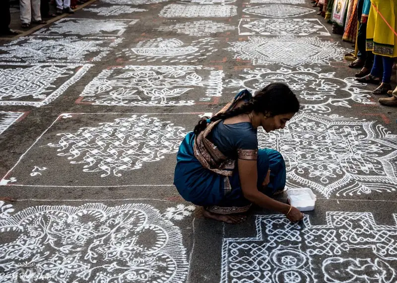 Indienne dessinant des mandalas sur le sol pendant les festivals de Kōlam, art ancestral indien symbolisant l'harmonie et la spiritualité