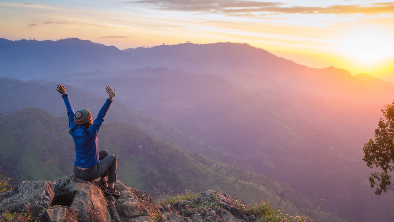 Woman in a posture of gratitude at sunrise, facing the mountains - a symbol of inner peace and morning meditation