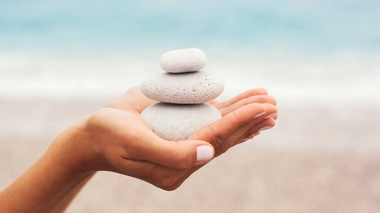 Woman holding pebbles stacked in balance in his hand, a symbol of centering, inner calm and vibrational harmony