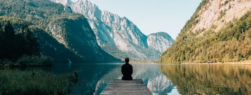 Man meditating in front of a lake, symbolizing tranquility, mindfulness, and inner connection through meditation