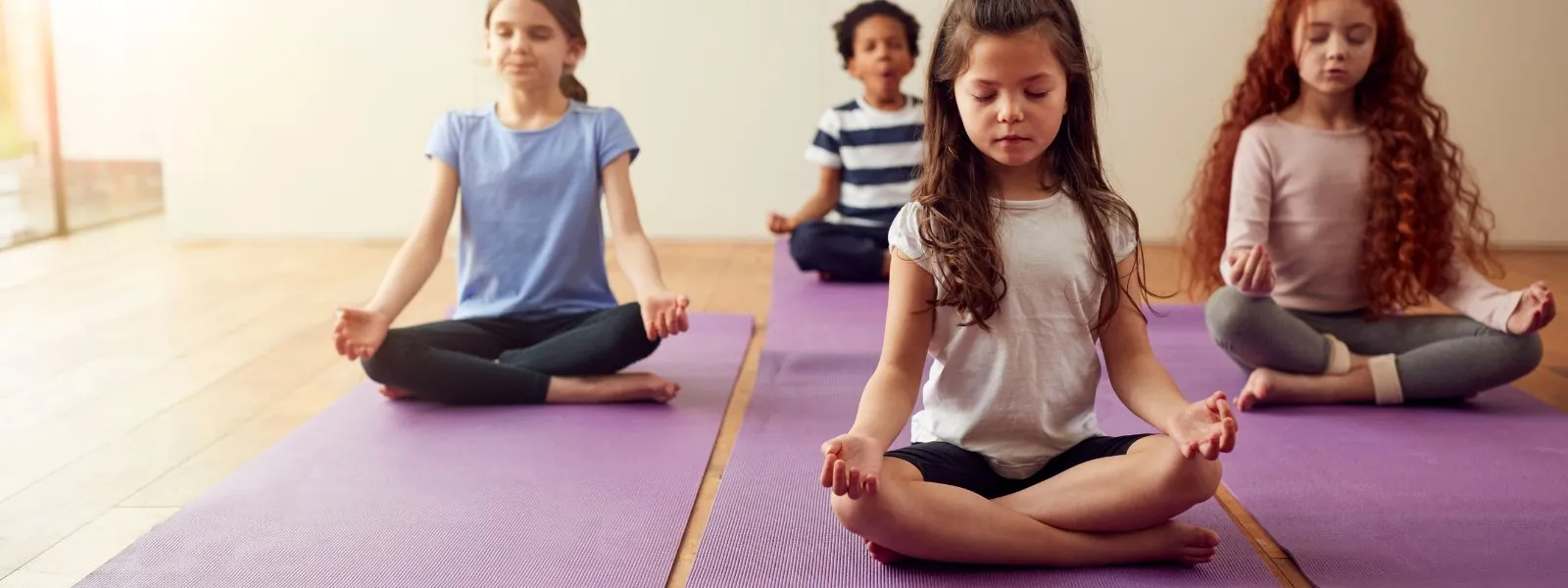 A group of children sitting in meditation poses, practicing mindfulness to strengthen their concentration, inner calm, and emotional balance