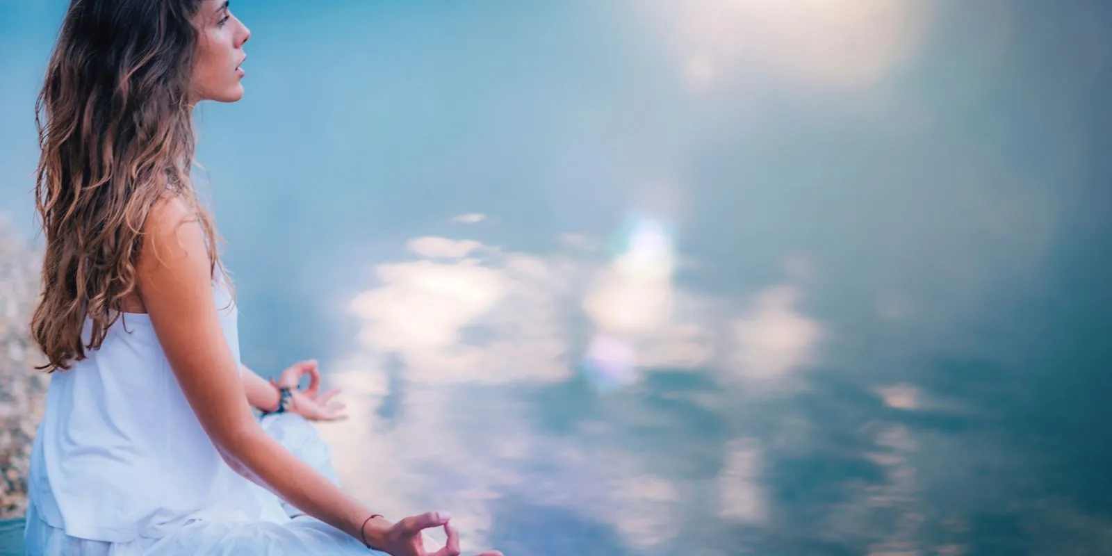 Frau, die an einem See meditiert, symbolisiert Loslassen, inneren Frieden und die Verbindung mit der Natur