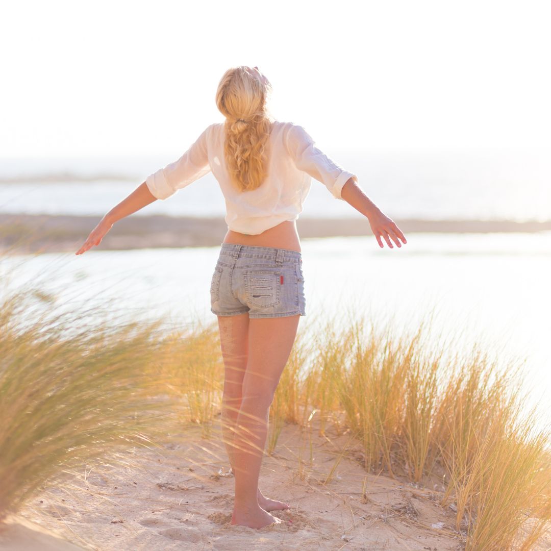 Femme debout dans la nature, en harmonie avec les éléments, représentant l’éveil spirituel et l’unité avec le monde