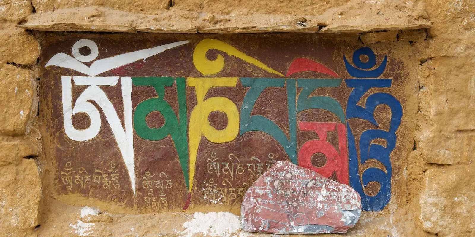 Mantra Om Mani Padme Hum in tibetischer Sprache an eine Wand gemalt, Symbol für Mitgefühl und Schutz im Buddhismus