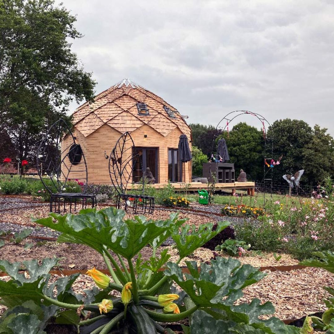 Zome en bois construit par Alterhabitat, entouré d’un jardin verdoyant, alliance nature et géométrie sacrée