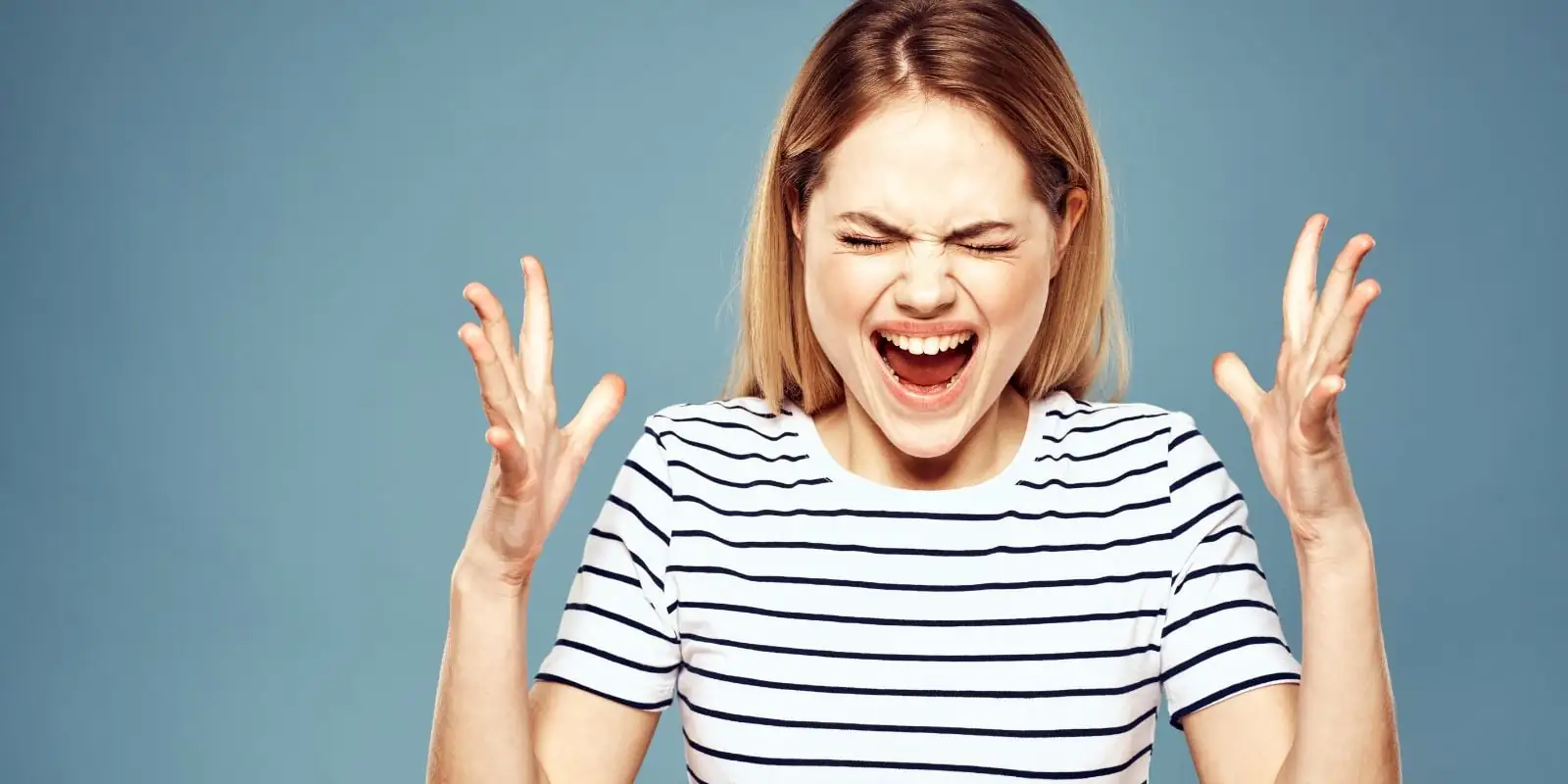 Mujer enojada y gritando, con las manos abiertas a ambos lados, simbolizando la expresión de ira y el desafío de mantener la calma