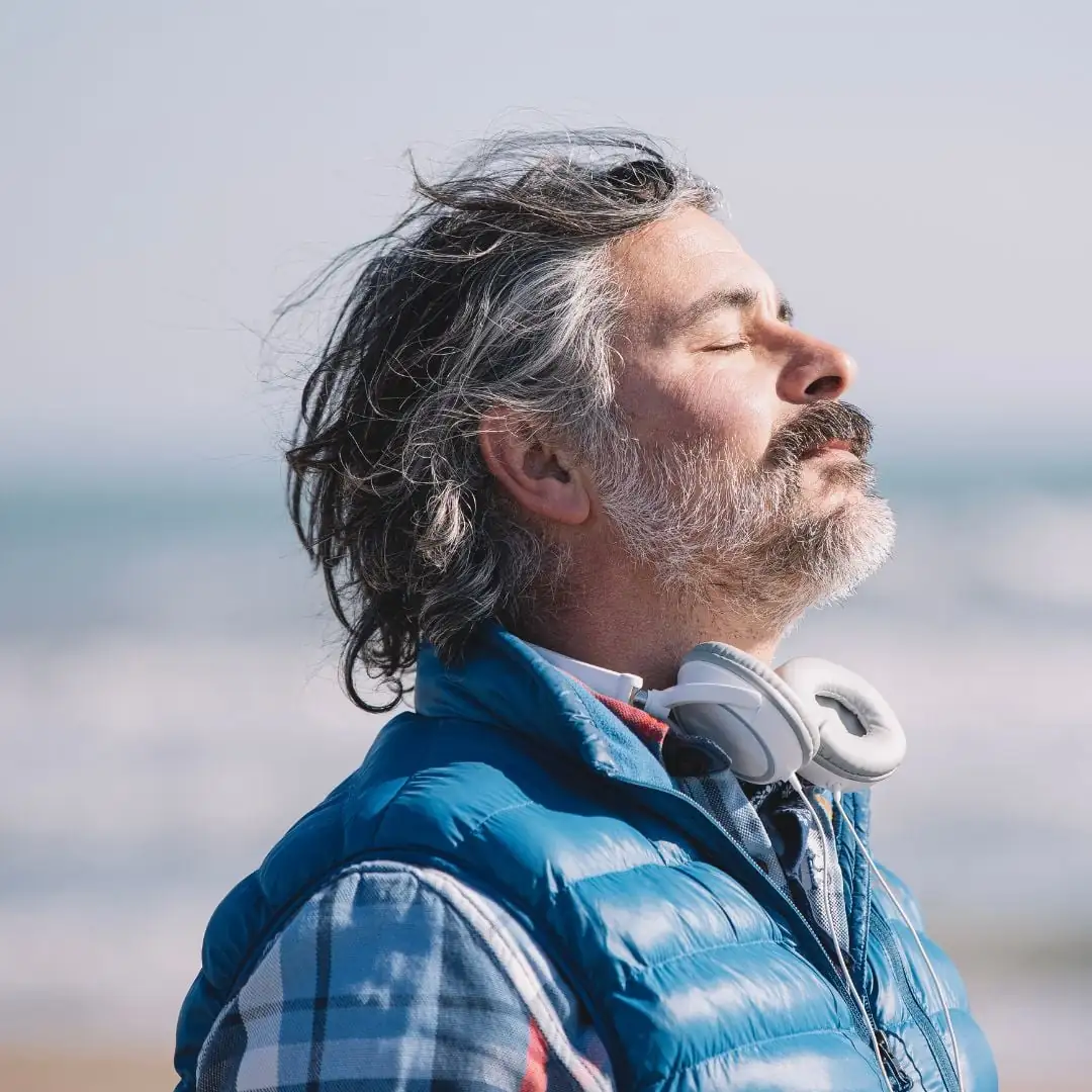 Hombre maduro practicando respiración profunda, utilizando esta técnica para recuperar la serenidad, reducir el estrés y calmar su mente